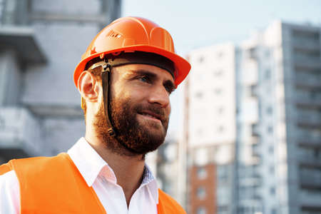 Builder wearing hardhat and safety vest standing on a commercial construction siteの写真素材