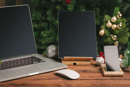 Close up shot of digital device on wooden table with christmas decorationsの写真素材