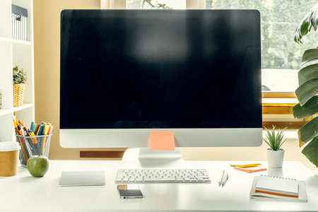 Office or home workspace. Computer monitor with black screen on office table with suppliesの写真素材