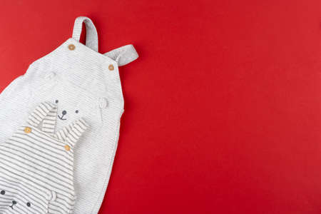 Baby clothes top view on red backgroundの写真素材