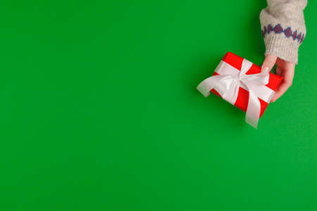 Woman hands holding gift box on green backgroundの写真素材