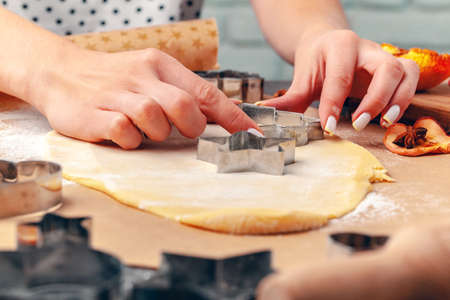 female hands making cookies from fresh dough at home
