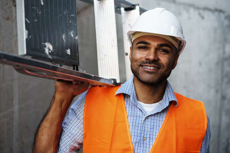 Professional builder carrying metal ladder, close upの写真素材