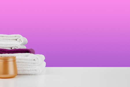 Pile of towels, bottles with shampoo on white tableの写真素材