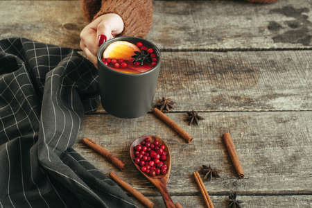 Womans hands in warm sweater holding a cup of mulled wineの写真素材