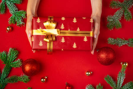 Hands of woman holding christmas gift box on a red backgroundの写真素材
