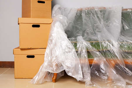 Packed household stuff in boxes and packed sofa for moving