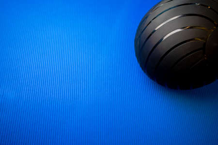 Black fitness ball on blue mat backgorund