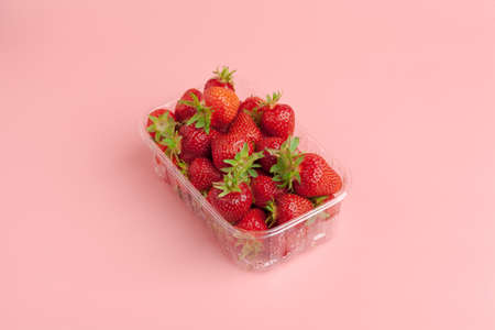 plastic basket of strawberries on pastel pink backgroundの写真素材