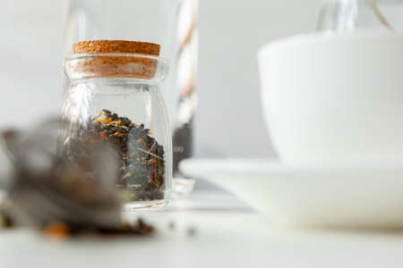 Glass jars with dry tea leaves close up on white tableの写真素材