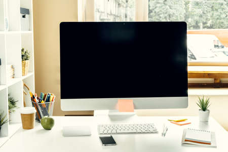 Office or home workspace. Computer monitor with black screen on office table with supplies