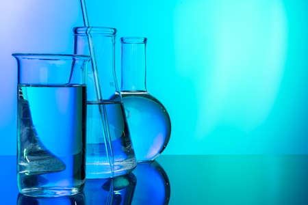 Row of test tubes with liquids on blue and green toned backgroundの写真素材