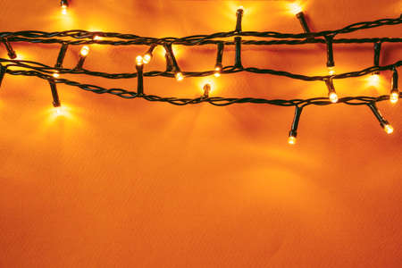 Orange background with illuminated lights of garland