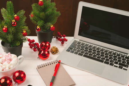 Open notepad and computer on table with christmas decorの写真素材