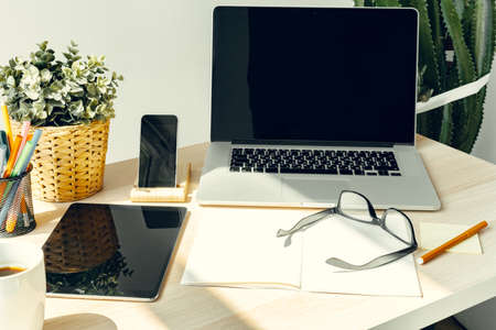 Laptop in a light room on working table with office supplies