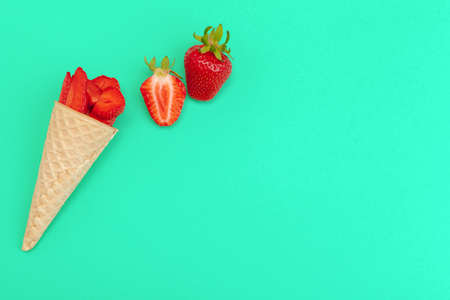 Waffle cone with fresh strawberries on vibrant background