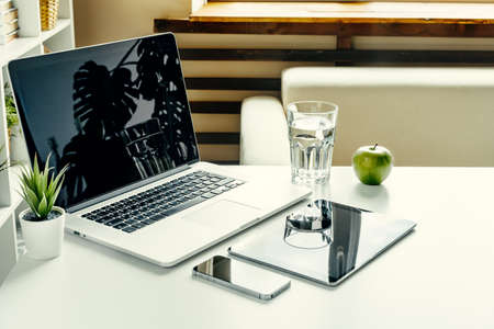 Open laptop on table near sofa, home interior. Freelancer workplace concept