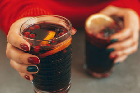 Womans hands in warm sweater holding a cup of mulled wine