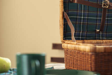 Wooden basket for picnic with plates, cups and silverware close up