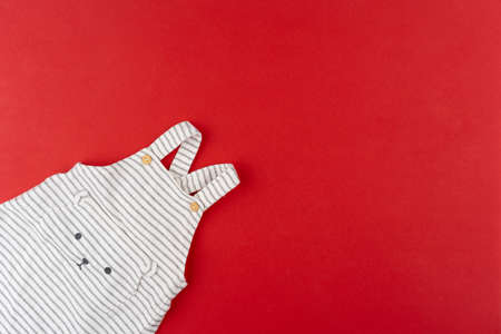 Baby clothes top view on red backgroundの写真素材