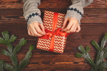 Woman holding wrapped Christmas present in her hands, view from aboveの写真素材