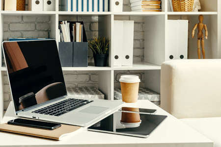 Open laptop on table near sofa, home interior. Freelancer workplace concept