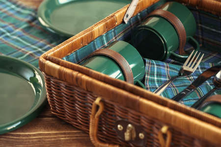 Wooden basket for picnic with plates, cups and silverware close upの写真素材