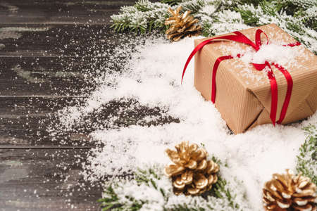 Beautiful Christmas gift with snowy holiday decorations on tableの写真素材