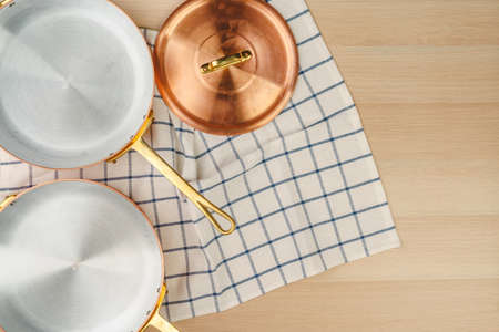 Copper frying pan on wooden background, top view