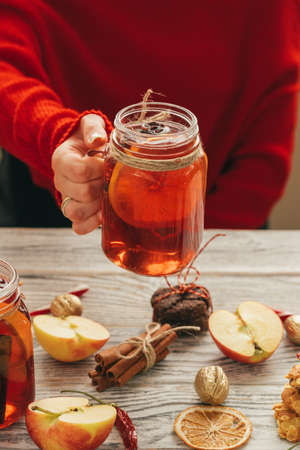 Cup of mulled wine in womans hands on wooden tableの写真素材