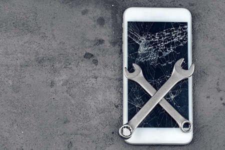 Crashed smartphone with repairing tools on grey backgroundの写真素材
