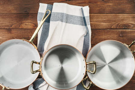 Clean shiny copper kitchenware on wooden boardの写真素材