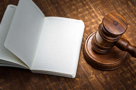 Brown wooden judge mallet on the background of open book