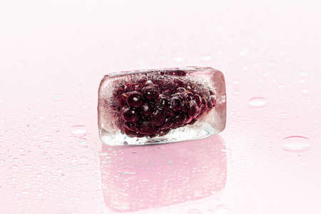 Frozen berries in ice cubes on pink