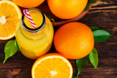 Bottle of orange juice with oranges on wooden tableの写真素材
