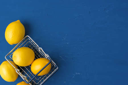 Lemon in shopping cart on classic blue background, top viewの写真素材