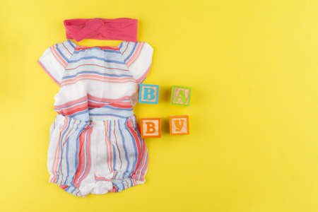 Top view of baby girl clothes on yellow backgroundの写真素材