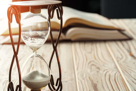 Closed up of sandglass or hourglass on background of bookの写真素材