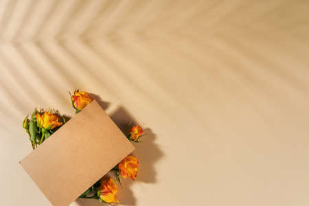 Craft paper envelope with yellow roses on beige background