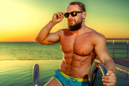 Fit man bodybuilder coming out of poolの写真素材