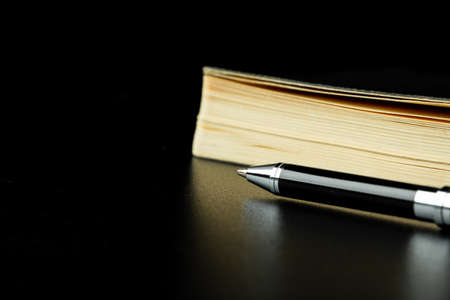 Black notepad with pen on black table close upの写真素材