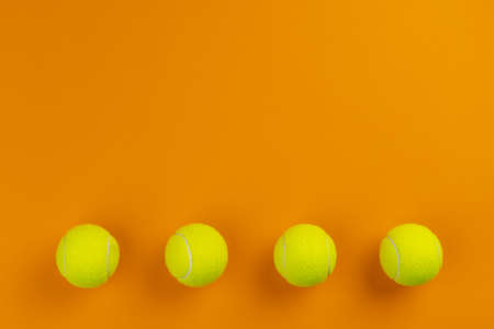 Four tennis balls on an orange backgroundの写真素材