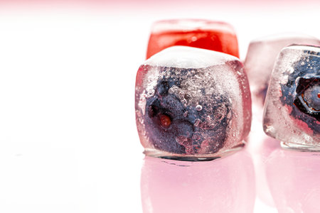 Fresh berries frozen in ice cubes for drinksの写真素材