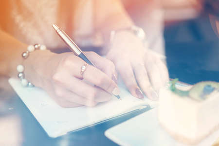 Woman making notes while sitting in a coffee shopの写真素材