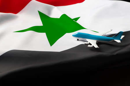 Small toy plane over the fabric flag of Syriaの写真素材