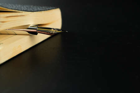 Black notepad with pen on black table close upの写真素材