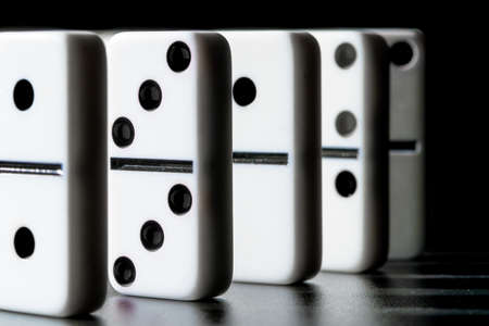 Dominoes standing in a row on black backgroundの写真素材