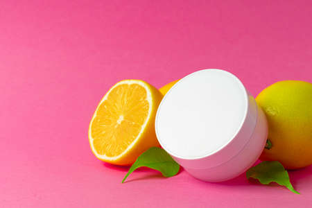 Cosmetic bottle with sliced citrus fruits on bright pink backgroundの写真素材