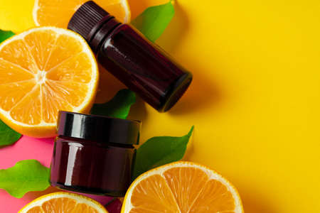 Citrus essential oil. Sliced citrus fruit and aroma bottles on pink backgroundの写真素材