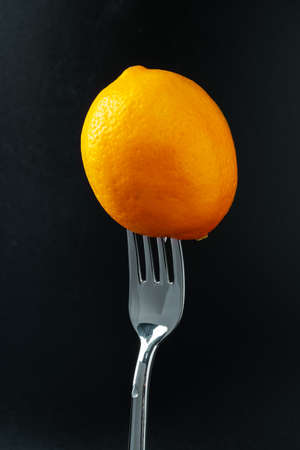 lemon on the fork on black backgroundの写真素材